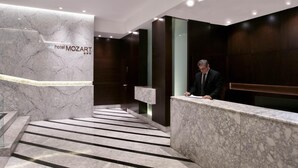 A hotel lobby with a marble reception desk, a staircase, and a modern design. - Hotel Mozart (Valladolid)