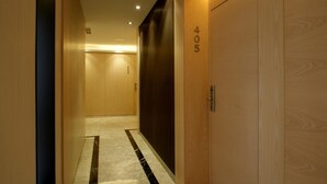 A hallway with wooden doors, a marble floor, and a number '405' on one door. - Hotel Mozart (Valladolid)