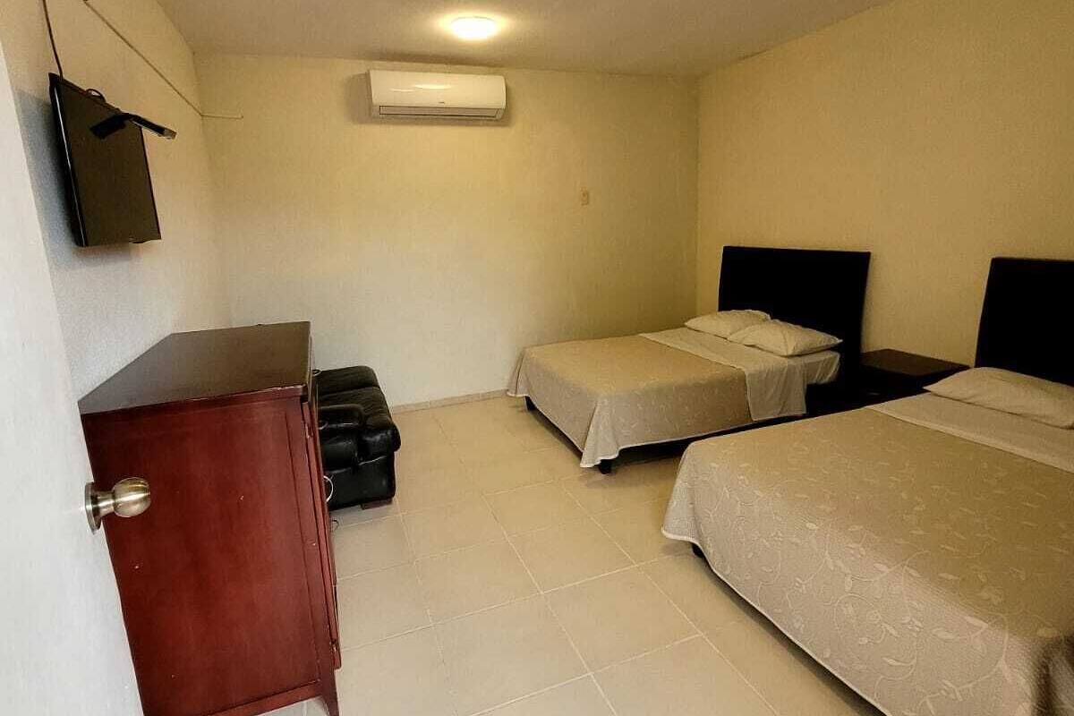 Een kamer met twee bedden, een bureau, een stoel en een airconditioning.