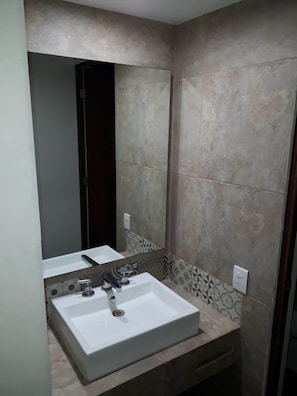 A bathroom with a large mirror, a white sink, and patterned tiles on the walls. - Hotel Vista Verde (Axtla de Terrazas)