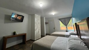 Habitación de hotel con dos camas, un televisor, un banco, un papel tapiz estampado y una puerta.