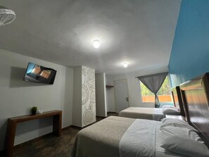 Ein Hotelzimmer mit zwei Betten, einem Fernseher, einer Bank, einer Wand mit Muster und einer Tür.