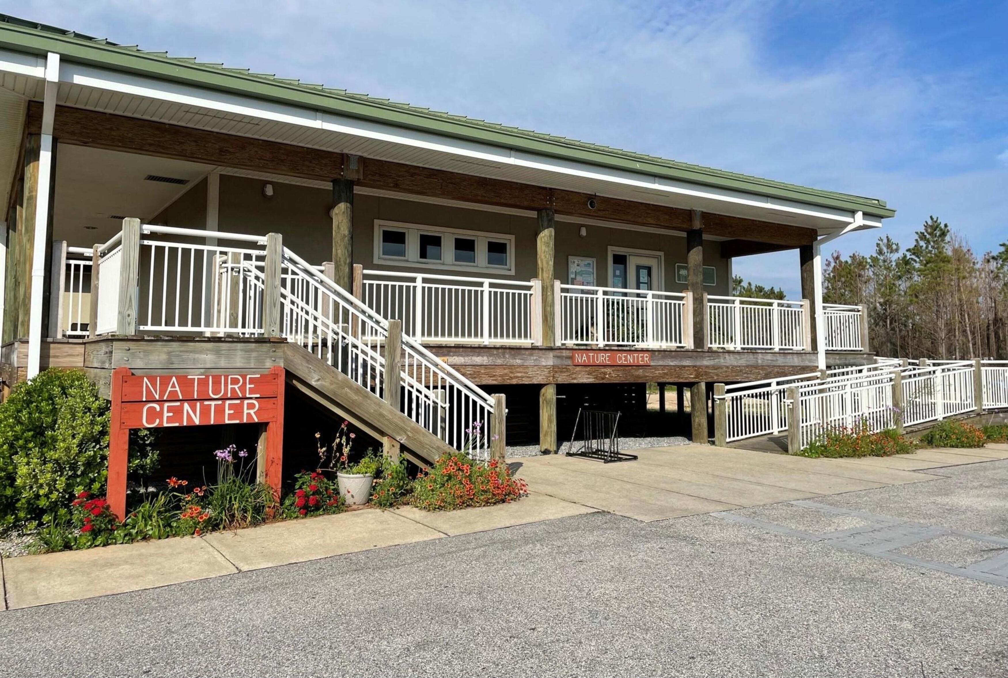 A building with a sign reading 'NATURE CENTER' and a covered outdoor area with a wooden deck and railing.