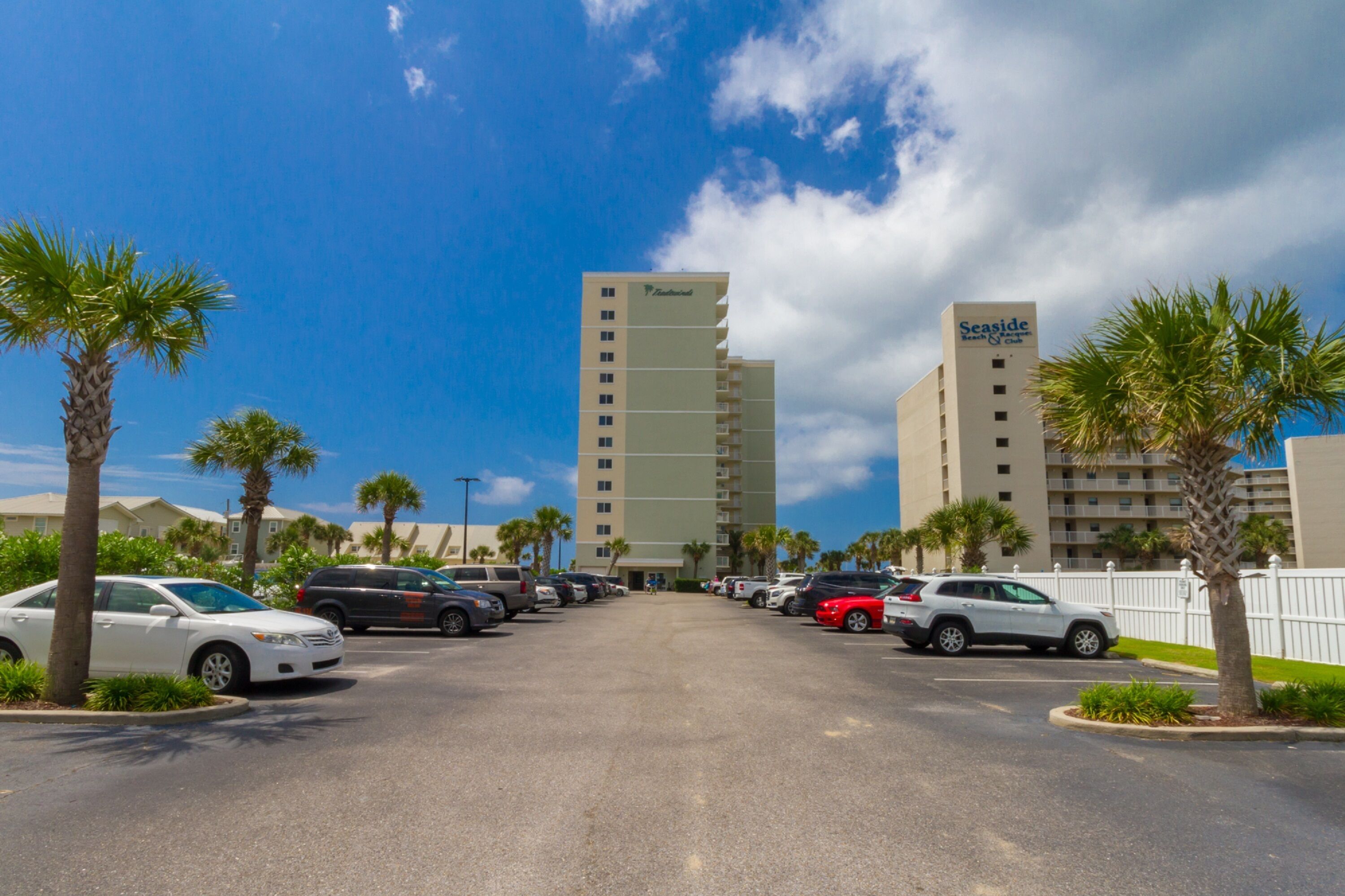 A parking lot with several cars, palm trees, and two tall buildings labeled 'Seaside' in the background.