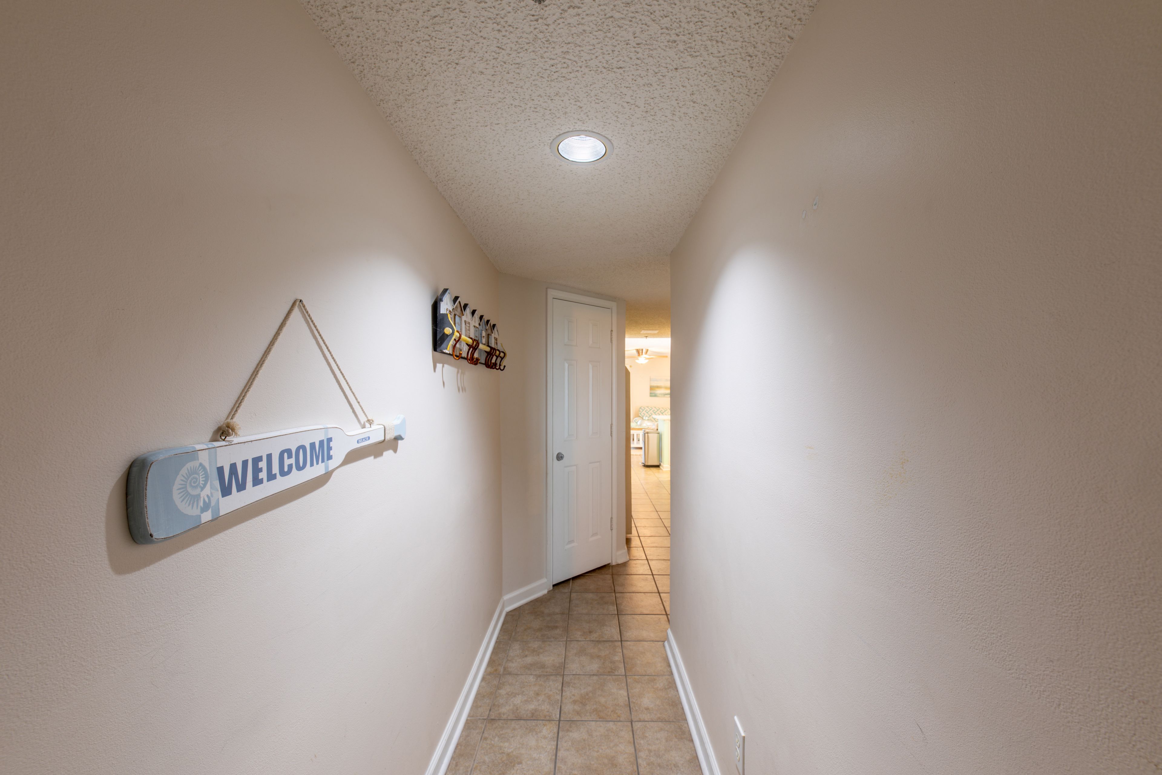 Un pasillo con un letrero de bienvenida, una puerta y piso de baldosas.