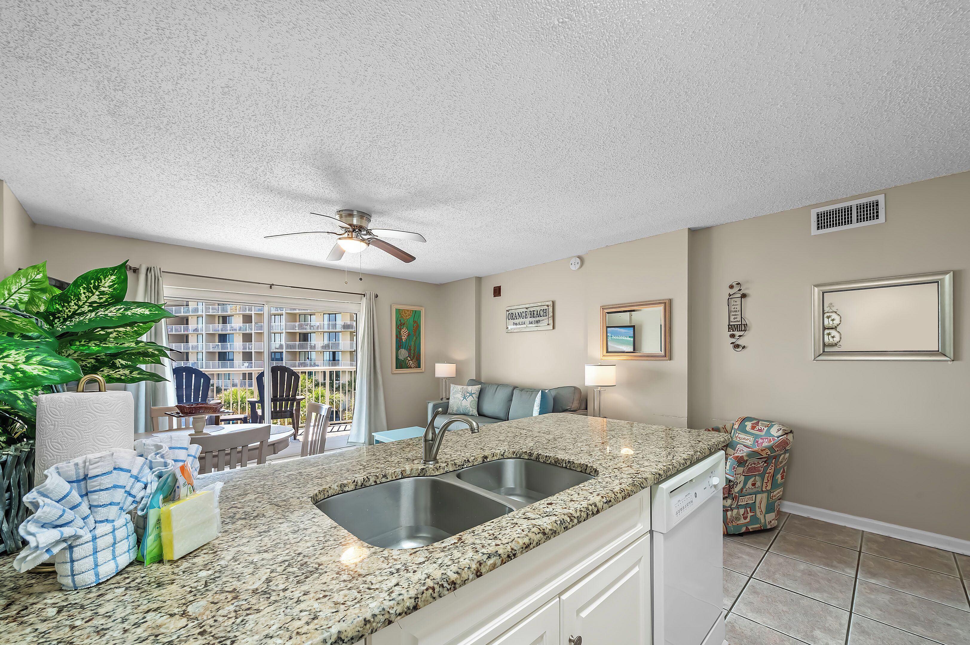 A kitchen with granite countertops, a double sink, and a dishwasher.