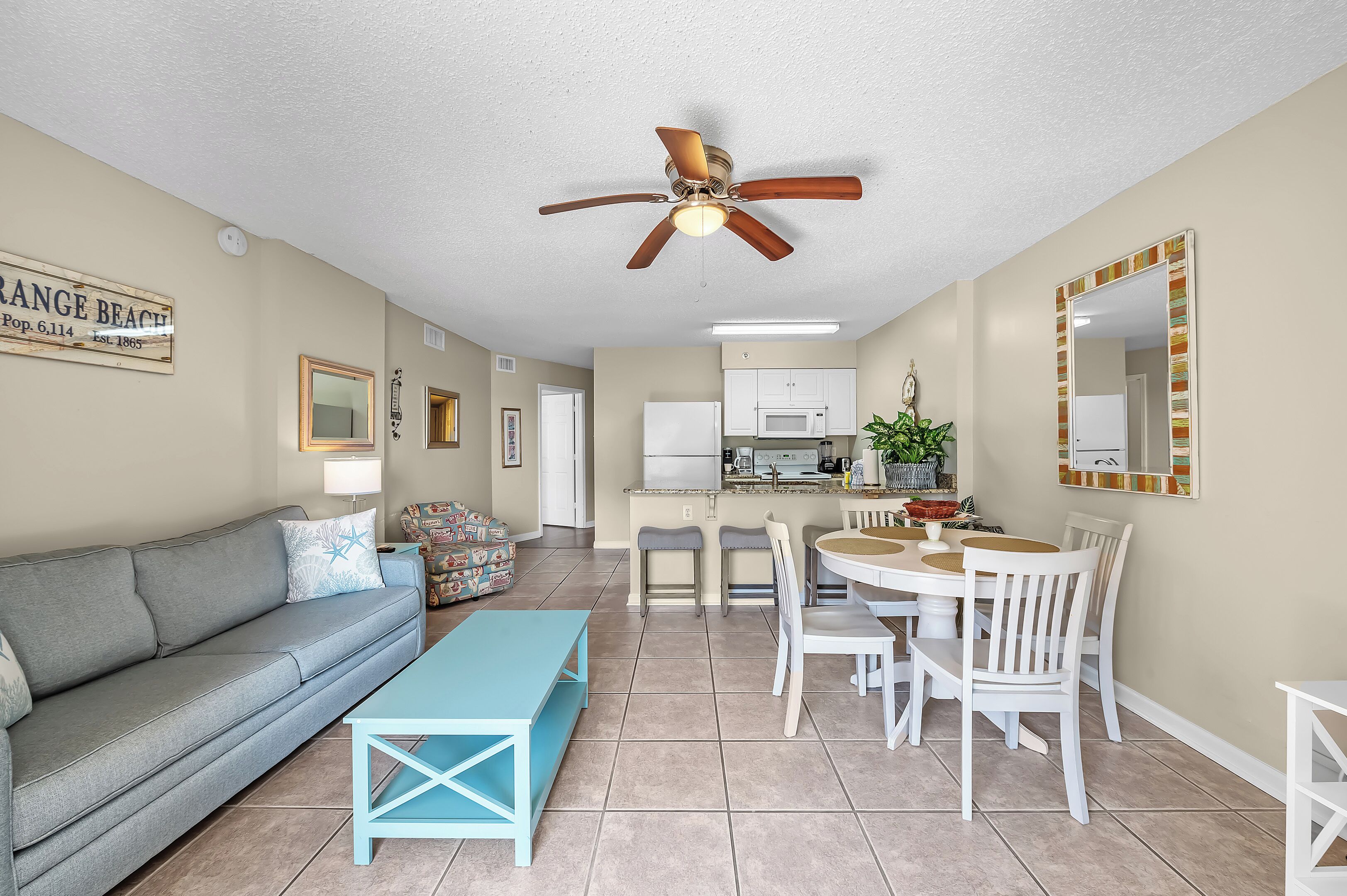 A living room with a gray sofa, a blue coffee table, and a ceiling fan.