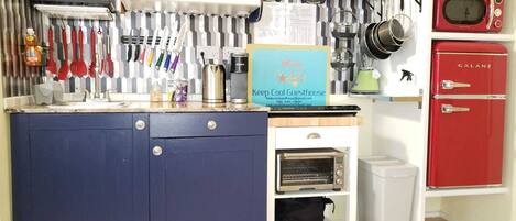 Una cocina compacta con un armario azul, un refrigerador Galanz y un microondas.