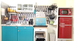 Una cocina compacta con gabinetes verde azulado, un microondas Galanz rojo y una cafetera.