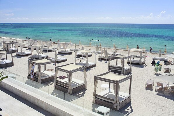 A beachside hotel with multiple sunbeds and umbrellas, a clear view of the ocean, and a sandy beach area. - Hotel Turquesa (Playa del Carmen)