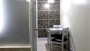 A small room with a white table and chair, a tiled wall, and a door. - Jardin de Rosal Hotel (Pasig)