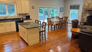 A spacious kitchen with a central island, wooden dining table with chairs, a cozy seating area with a leather couch, and a stone fireplace. - Upscale Mount Snow/Stratton Area w/Indoor Pool access, short drive to lakes  (West Wardsboro)