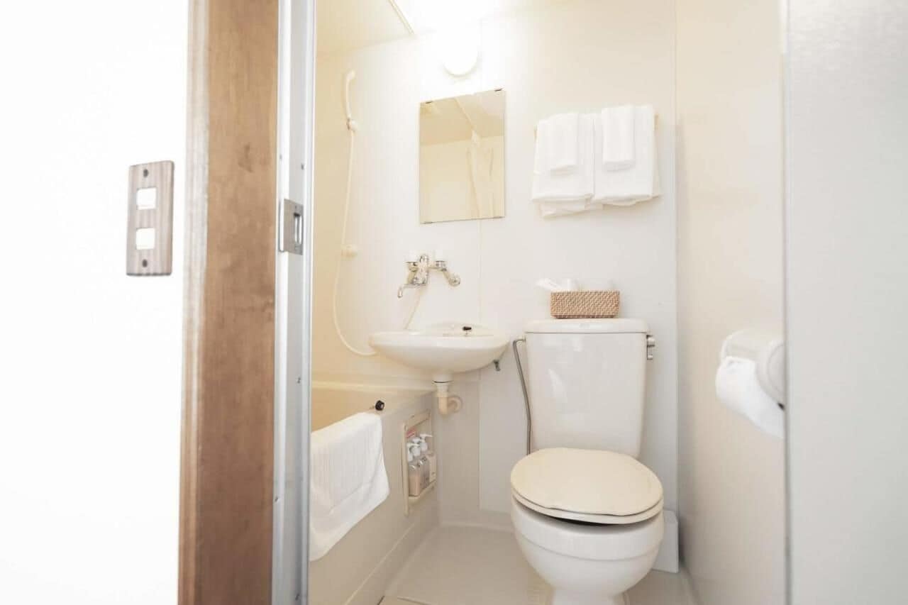 A compact bathroom with a toilet, sink, and shower.