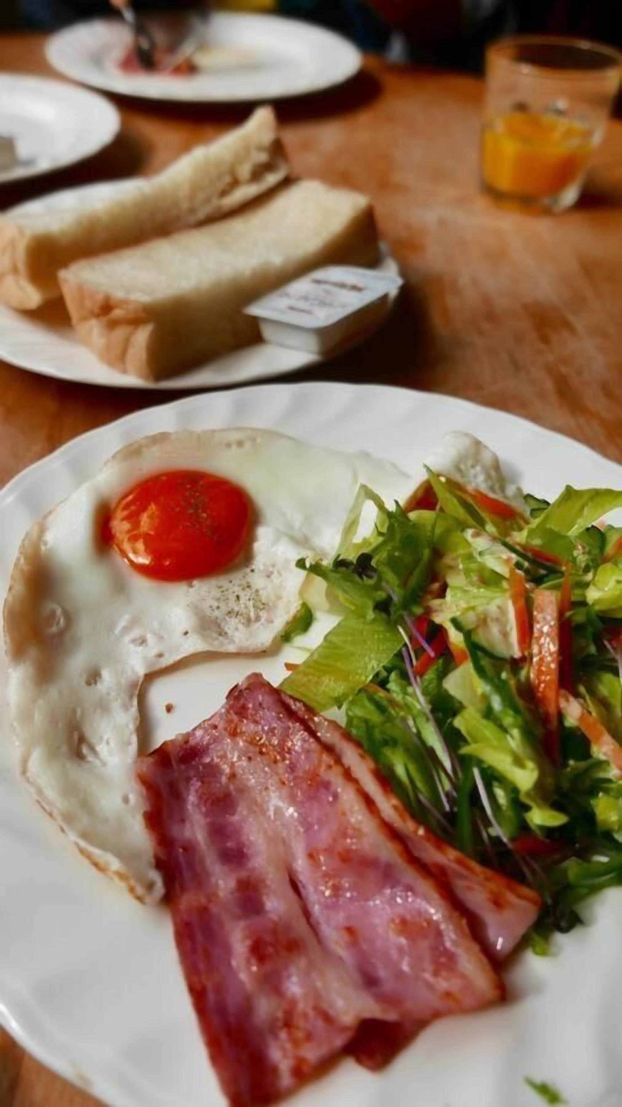 A plate with a fried egg, bacon, and a salad.