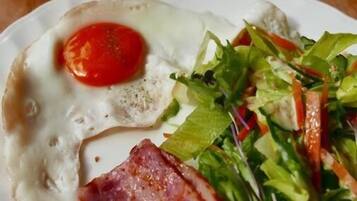 A plate with a fried egg, bacon, and a salad.