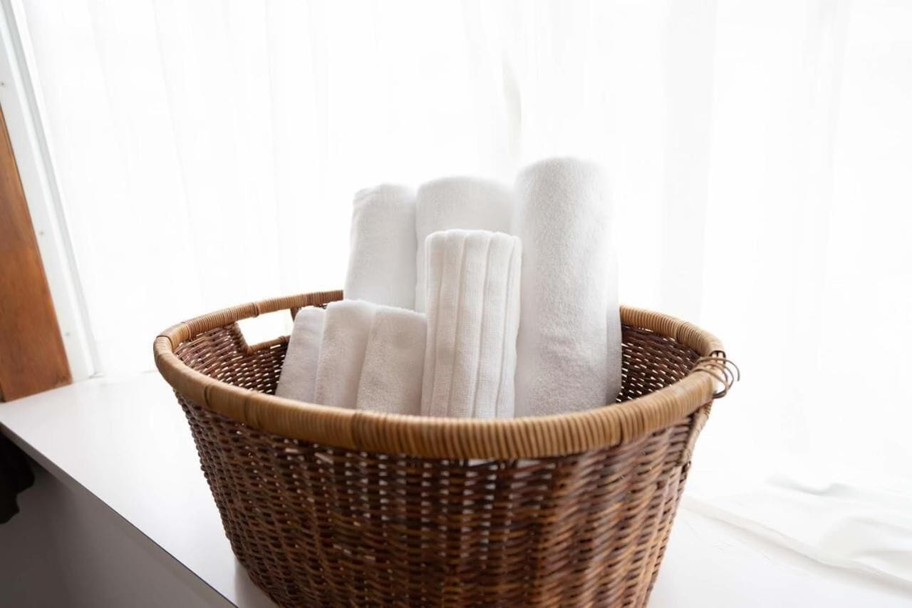 A wicker basket filled with white towels placed on a windowsill.