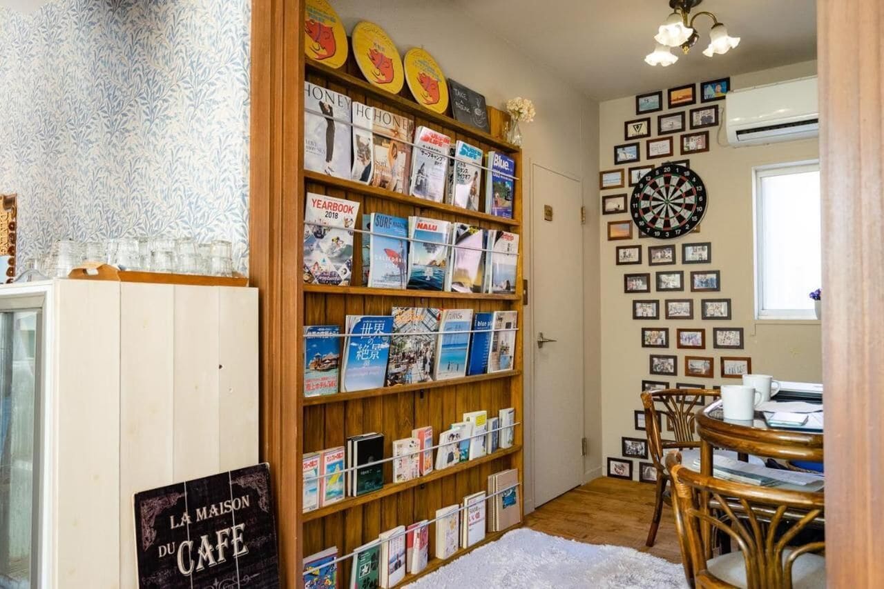 Een gezellige kamer met een boekenplank vol boeken, een dartbord en een salontafel met stoelen.