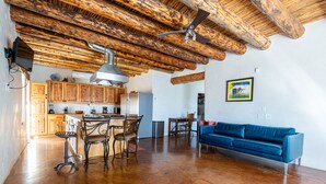 Un vaste espace de vie doté d’un plafond en bois, d’un canapé bleu et d’une cuisine avec des meubles en bois.