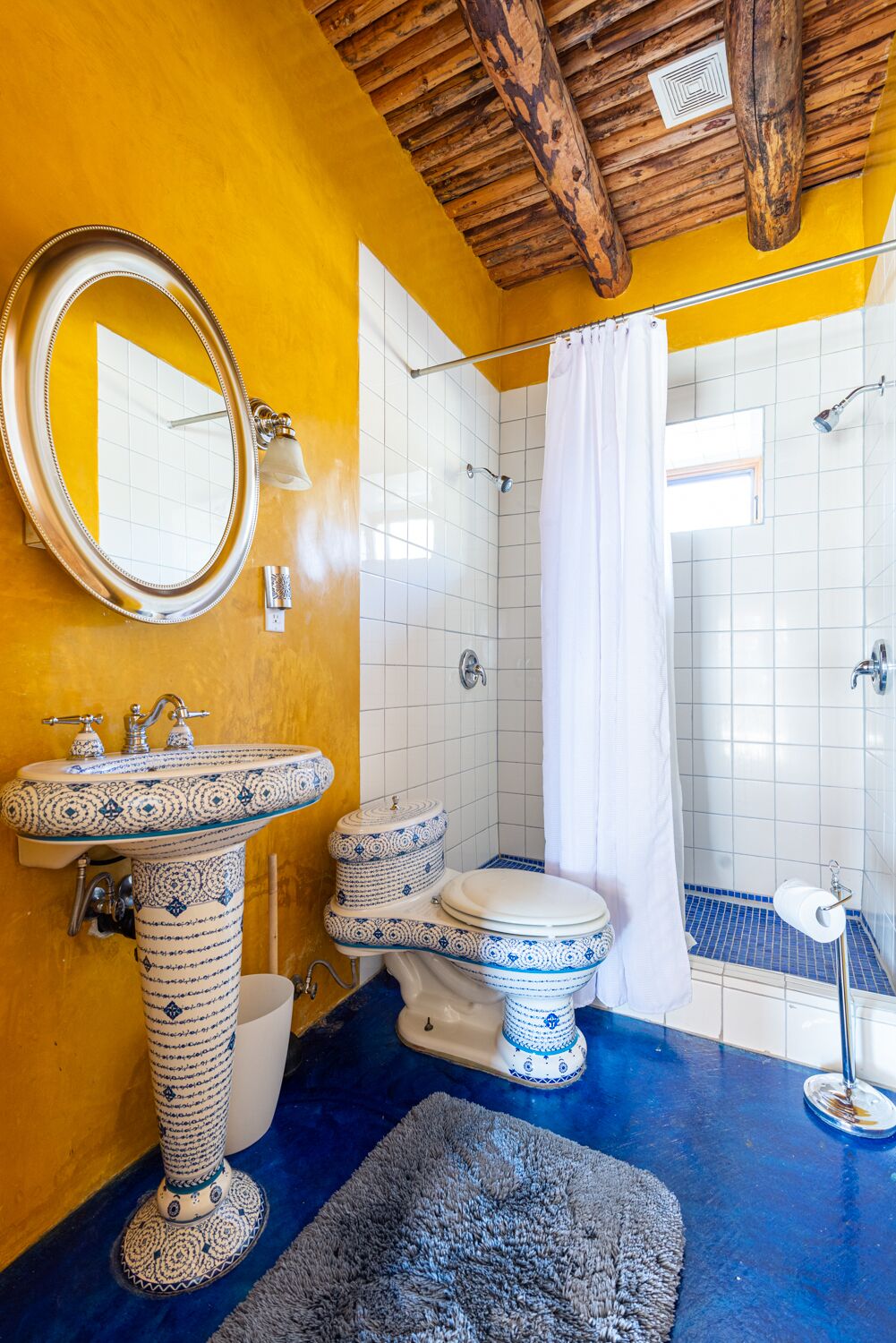 A bathroom with a wooden ceiling, a large sink, a toilet, and a shower area.