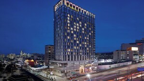 A high-rise hotel with a modern glass facade, multiple floors, and illuminated windows. - L7 HONGDAE by LOTTE HOTELS (Seoul)