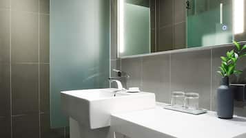 Un baño moderno con lavamanos blanco, un espejo grande y cabina de ducha de cristal.