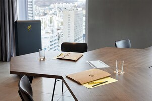 A conference room with a wooden table, two chairs, a glass, a folder, and a pen.