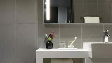 A modern bathroom with a white toilet, a white sink, and a mirror above the sink.