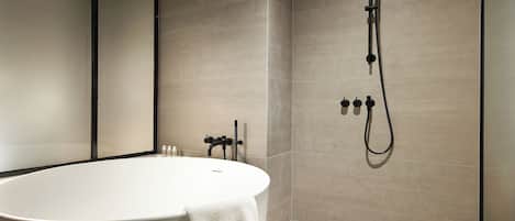 A modern bathroom with a freestanding bathtub, a wall-mounted shower, and a visible toilet.