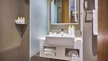 A modern bathroom with a sink, mirror, towel rack, and a shelf with toiletries.