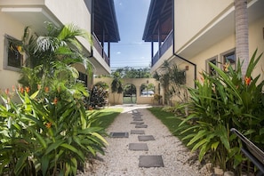 Stroll through the tranquil courtyard, surrounded by lush tropical plants and palm trees, and enter through the central archway.
