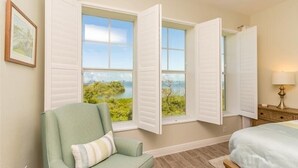 Une chambre à coucher avec un lit, une chaise et une fenêtre avec des volets.