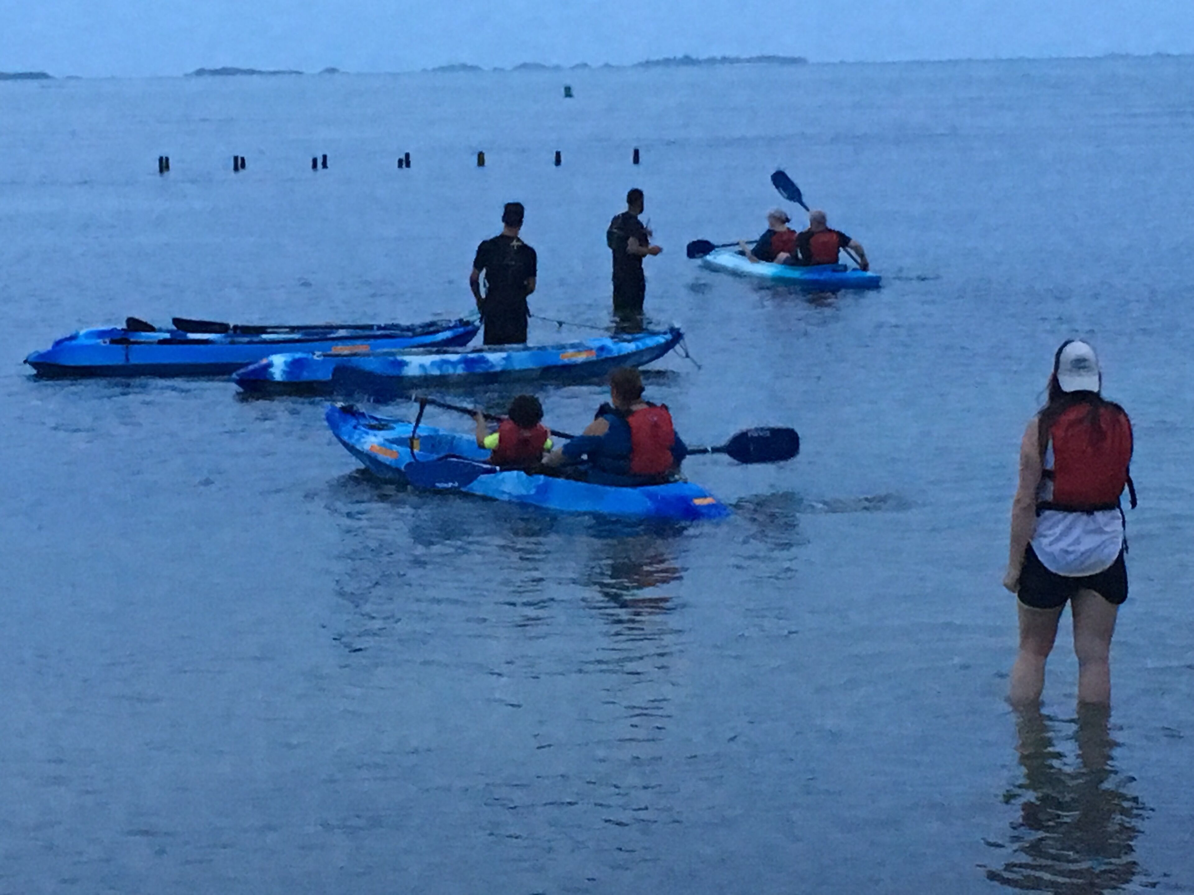 Un groupe de personnes pratiquant le kayak sur une étendue d’eau calme.