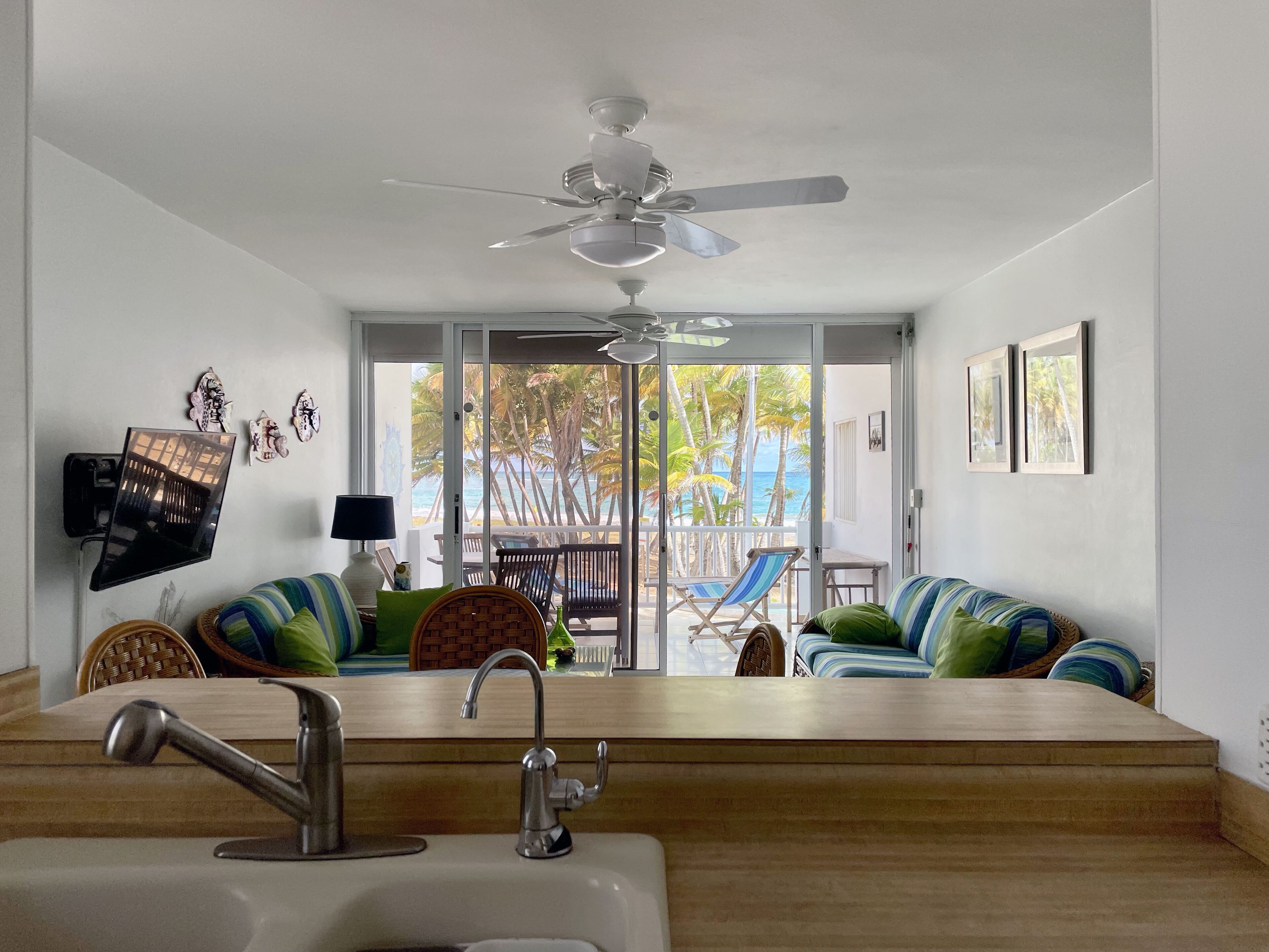 A modern kitchen with a wooden countertop, a sink, and a ceiling fan.