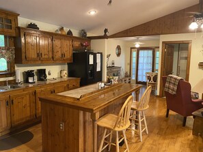 Una cocina con armarios de madera, un refrigerador negro y una isla de madera con taburetes de bar.
