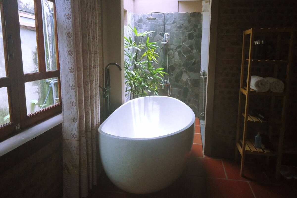 A bathroom with a large bathtub, a shower, and a wooden shelf with towels.