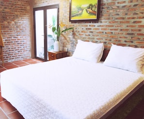 Relax in a serene space with a large bed, brick wall, and a window offering a view.