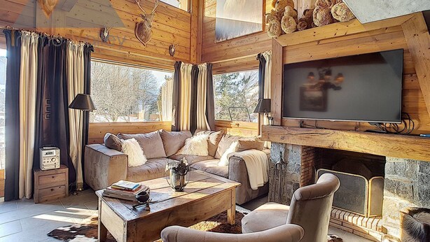 A cozy log cabin interior with a fireplace, a television, and a sofa. - Triplex apartment in chalet, spectacular view of Megève and the Alps (Demi-Quartier)