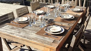 A wooden dining table set outdoors with chairs, plates, glasses, and cutlery. - Triplex apartment in chalet, spectacular view of Megève and the Alps (Demi-Quartier)