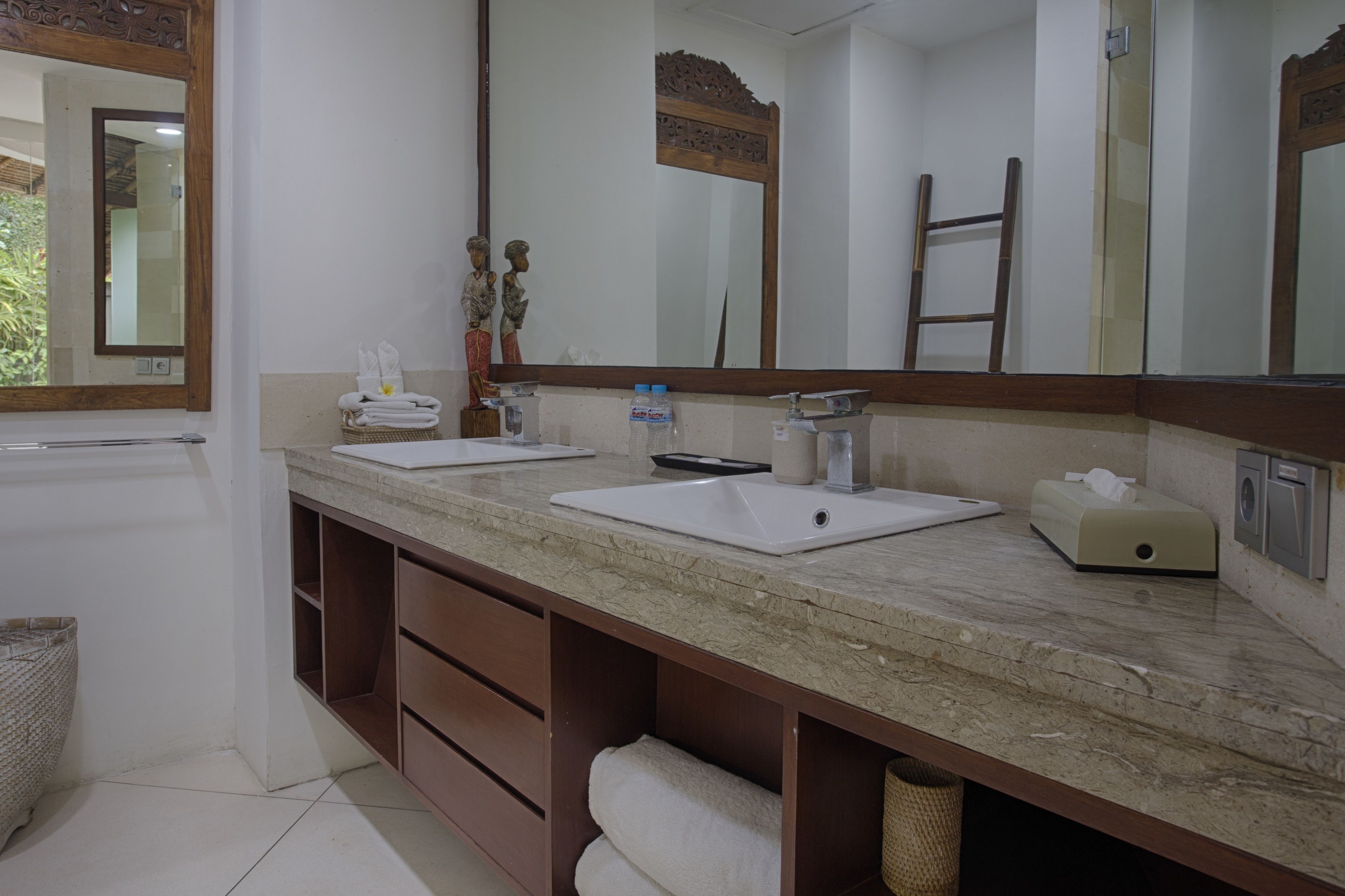 A bathroom with two sinks, a large mirror, a towel rack, and a wooden shelf.