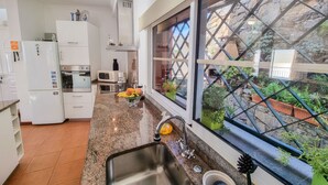 Eine moderne Küche mit weißen Schränken, einer Arbeitsplatte aus Granit und einem Fenster mit Blick auf einen Garten.