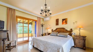 A spacious bedroom with a large bed, wooden headboard, and two bedside tables with lamps.