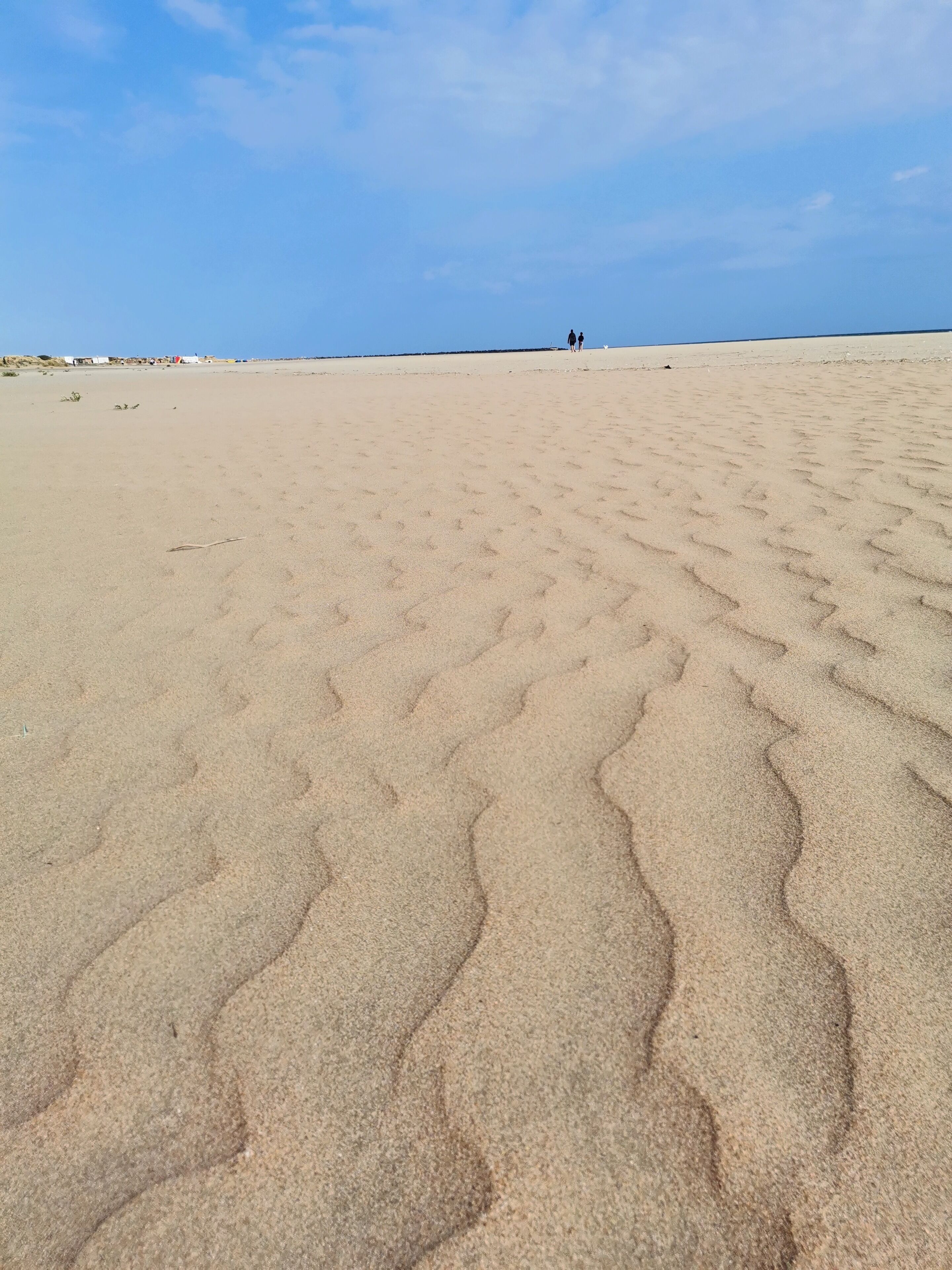 A sandy beach with footprints leading towards the horizon.