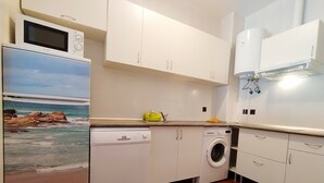A compact kitchen with white cabinets, a microwave, a dishwasher, and a washing machine. - Punta Umbria, Huelva Andalucia Costa de la Luz 2 bedrooms swimming pool  (Punta Umbría)