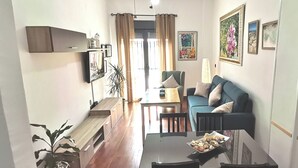A living room with a sofa, a dining table, and a coffee table. There is a plant on the left and a lamp on the right. - Punta Umbria, Huelva Andalucia Costa de la Luz 2 bedrooms swimming pool  (Punta Umbría)