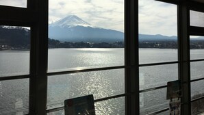 A view of a mountain through a window, with a body of water in the foreground. - Tominoko Hotel (Fujikawaguchiko)