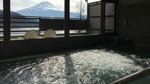 A hot spring area with a view of a mountain. There are chairs and a bench near the window. - Tominoko Hotel (Fujikawaguchiko)