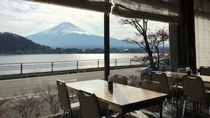 A restaurant with a view of a mountain and a lake. - Tominoko Hotel (Fujikawaguchiko)