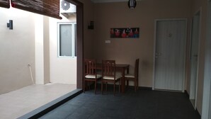 Una habitación pequeña con una mesa, sillas, una puerta y una ventana con persianas.