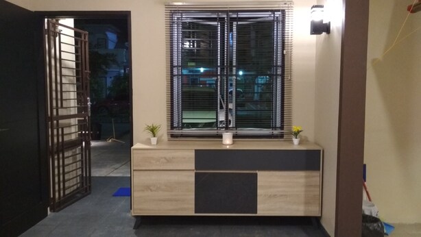 Una habitación con un armario de madera, una ventana con persianas y una pequeña planta en maceta sobre el mueble.