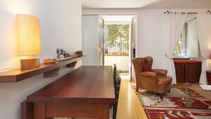 Amplia sala de estar con una mesa de comedor de madera, un sillón de cuero y un gran ventanal con cortinas.